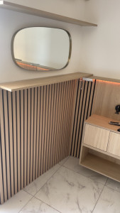 Photo de galerie - Réalisation d’un habillage mural en tasseaux bois avec tablette supérieure et intégration d’un éclairage LED indirect.