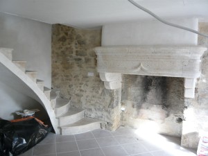 Photo de galerie - Une cheminée en pierre, un escalier en voute sarrasine, des joints de pierre, de l'enduit au plâtre, du carrelage.