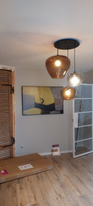 Photo de galerie - Radiateur design qui fait également office de cadre décoratif, alliant confort et esthétique. On peut également voir le luminaire composé de trois suspensions, apportant une touche moderne et élégante à la pièce.