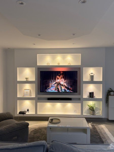 Photo de galerie - Aménagement mural sur mesure avec meuble TV intégré et niches décoratives éclairées par LED.
Structure en placo avec éclairage encastré et finition épurée, offrant un rendu moderne et chaleureux.