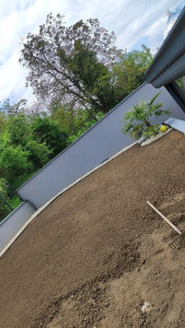 Photo de galerie - Pose de bordure aluminium avec geotextile + recouvrement en cailloux blanc.
travail de sol, avec ratissage et semis de gazon.
