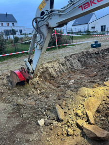 Photo de galerie - Cette photo illustre des travaux de terrassement réalisés à l’aide d’une mini-pelle, dans le cadre de la préparation du terrain avant les travaux de maçonnerie.