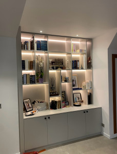 Photo de galerie - Bibliothèque sur mesure avec rangements intégrés et éclairage LED. Fabrication, agencement et pose avec finitions soignées.