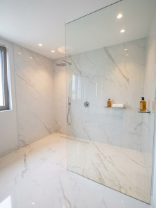 Photo de galerie - Réalisation d’une douche à l’italienne avec pose de carreaux grand format 270x120 cm effet marbre. Une finition haute de gamme apportant luminosité, continuité et élégance à l’espace.