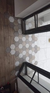 Photo de galerie - Raccord en hexagonal en cuisine marbre blanc et salon effet parquet. 