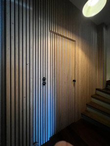 Photo de galerie - Découpe et pose d’un revêtement en latte de bois sur mur et porte de couloir + remplacement des interrupteurs 