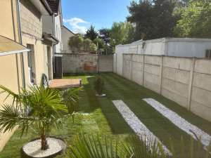 Photo de galerie - Pose de gazon naturel avec palmier et cailloux blancs 