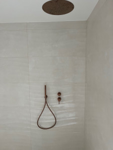 Photo de galerie - Une installation d’un corps encastré et d’un ciel de pluie avec des raccords précis pour assurer une installation durable et étanche. offrant un rendu moderne et minimaliste. L’ensemble témoigne d’un travail précis, pour une finition haut de gamme.