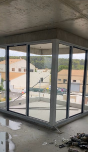 Photo de galerie - Pose d’une baie vitrée d’angle en aluminium avec profilés gris anthracite offrant une grande luminosité et une vue dégagée sur l’extérieur Travail soigné précision de pose et finitions de qualité.