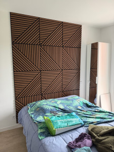 Photo de galerie - Pose de revêtement mural en tasseaux de bois avec assemblage géométrique et fixation murale.