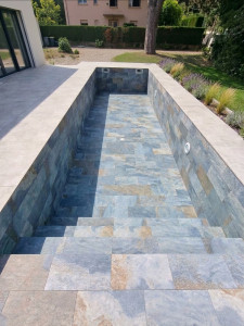 Photo de galerie - Piscine réalisée en carrelage 30 × 60 cm, imitation pierre de Bali, accompagnée d’une terrasse en dalles 120 × 120 cm.