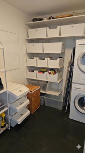 Photo de galerie - Aménagement d'une buanderie : installation d'un système d'étagères et d'un espace de rangement fonctionnel.