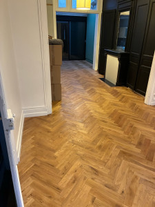 Photo de galerie - Rénovation d’un salon avec préparation complète du support et pose de parquet collé en bâtons rompus. Travail soigné, découpes précises et finitions réalisées avec soin.