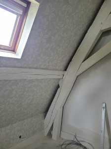 Photo de galerie - Pose d'un magnifique papier peint à raccord, avec des poutres peintes en blanches.