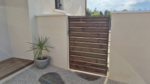 Photo de galerie - Création et réalisation sur mesure d'un portillon avec structure métallique coloris corten et planche de pin .