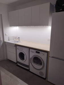 Photo de galerie - Buanderie : montage de meubles bas et haut, pose d'un plan de travail avec évier et robinet, installation d'une bande led, crédence en faïence en cours d'installation.