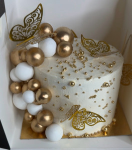 Photo de galerie - Gâteau d’anniversaire personnalisé blanc et doré, décoré de papillons, de perles et de sphères. ?✨ Réalisation sur mesure selon le thème et les couleurs souhaités.