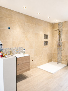 Photo de galerie - Pose de carrelage grand format dans une salle de bain avec douche à l’italienne, niches encastrées et finitions impeccables. Travail soigné et professionnel.