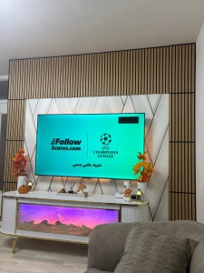 Photo de galerie - Option 1 (Complète) : Création d'un mur TV sur mesure avec tasseaux de bois acoustiques, panneau central décoratif géométrique et meuble suspendu avec éclairage LED.