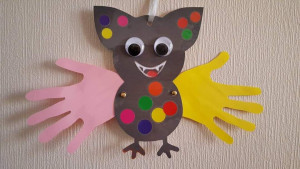 Photo de galerie - Activité manuelle avec un enfant en situation de handicap en utilisant la technique de dessin des mains, collage de gommettes, choix des matériaux.