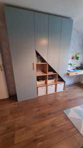 Photo de galerie - Armoire de rangement et son bureau suspendu pour une chambre d'enfants. Fabrication et pose de l'ensemble.
  Tout est fait en panneau plaqué chêne vernis et portes en MDF laquées. La poignée est elle en chêne massif vernis.