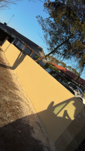 Photo de galerie - Mur de clôture terminé avec application d’un enduit ton pierre, finition grattée, offrant un rendu esthétique uniforme et durable