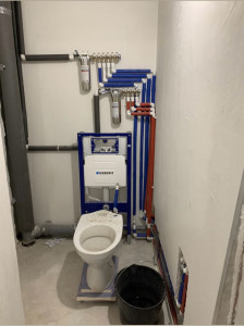 Photo de galerie - Préparation complète des installations sanitaires. Pose du bâti-support Geberit, alimentation en eau et évacuation réalisées avec précision avant les travaux de finition.