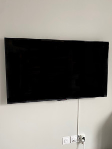 Photo de galerie - Fixation d’une télé au mur et raccord électrique soigné.