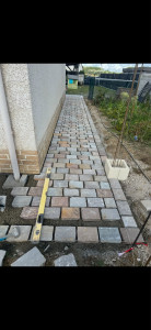 Photo de galerie - Création d’une allée pavée en pierre naturelle avec pose soignée et alignement nivelé le long de la maison.
