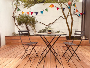 Photo de galerie - Changement d'une terrasse en mauvaise état dans une cours intérieur. Repeindre les murs pour apporter plus de luminosité et choisir un bois exotique (le cumaru) pour donner de la chaleur et du peps à l'ensemble. Petit aménagement banc de rangement.