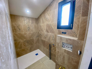 Photo de galerie - Réalisation d’une salle de bain pour un studio : pose du bac à douche , étanchéité du sol et murs , installation bâti support wc suspendu geberit , pose travertin 60x40 au mur