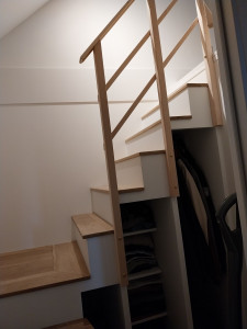 Photo de galerie - Réalisation d'un escalier sur mesure, hors gabarit standard de trémie avec assemblage de plusieurs caissons pour agencer un espace de rangements gain de place, sur-marches en chêne massif et garde-corps.