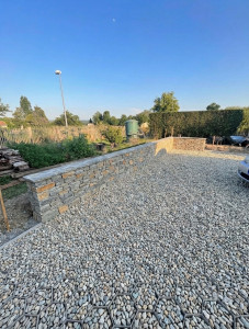 Photo de galerie - Réalisation d’un muret maçonné en parpaings, avec pose d’un parement en pierre naturelle et finition par couvertines. Un ouvrage alliant solidité, durabilité et esthétique, parfaitement intégré à l’aménagement extérieur.