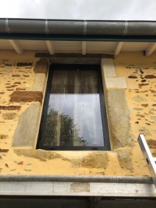 Photo de galerie - Pose châssis alu vitré fixe dans une ancienne grange garnissage étanchéité entre mur au mortier ton pierre 