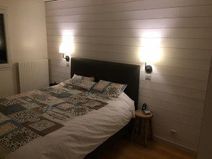 Photo de galerie - Aménagement d'une chambre avec mur en lambris pin naturel clair et éclairages tête de lit