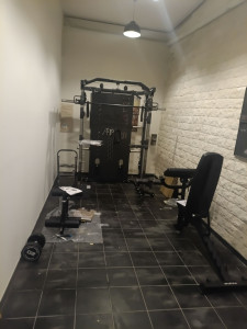 Photo de galerie - Aménagement complet d’un espace de musculation avec installation d’une cage multifonction, d’un banc de musculation et de différents équipements sportifs. Travail réalisé avec soin pour optimiser l’espace et créer une salle fonctionnelle et esthétique.