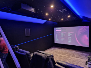 Photo de galerie - Création d'une salle de cinéma pour un particulier, incluant une plafond acoustique avec spot led et ciel étoilé, mur acoustique avec bandeau led, pose d'enceintes, rétroprojecteur et écran.