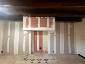 Photo de galerie - Démolition d’une vieille cheminée et du doublage endommagé par l’humidité, pose de plaques de plâtre et traitement des bandes pour accueillir un poêle.