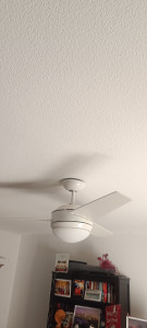 Photo de galerie - Remise en place et fixation sécurisée d’un ventilateur de plafond décroché. Contrôle de la stabilité de l’ensemble et vérification du bon fonctionnement après intervention.