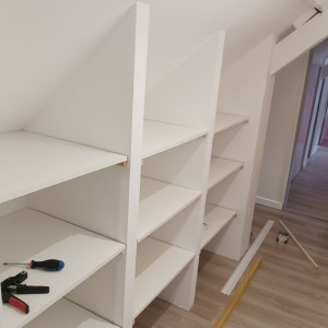 Photo de galerie - Réalisation d étagère de rangement 
 sous pente dans un couloir 