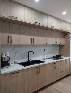 Photo de galerie - Pose de cuisine avec un plan de travail de texture marbré, façade en bois avec un poste haute et bas 