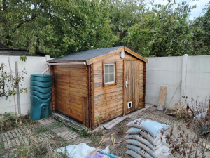 Photo de galerie - Remise en état d'un abri de jardin avec Rehaussement, changement de lattes, renforcement de l'abri, ponçage, peinture (lasure)au pistolet, création d'une dalle béton avec évacuation des eaux de pluie. 