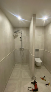 Photo de galerie - Rénovation complète d’une salle de bain : pose de carrelage mural et au sol, installation d’une douche à l’italienne avec caniveau, montage d’un WC suspendu, robinetterie, finitions soignées et alignement précis des revêtements.