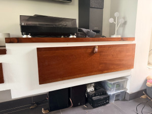 Photo de galerie - Création sur mesure d'une porte pour un meuble télé, ainsi qu'un dessus du meuble avec recouvrement à l'avant. Bois noble rouge vernis. Le tout réalisé sur mesure.