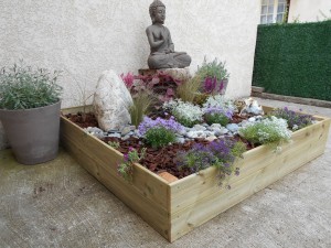 Photo de galerie - Aménagement floral d'une petite cour avec un bac à sable.