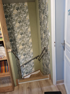 Photo de galerie - Fin des travaux dans la cage d’escalier : murs entièrement repris, surfaces redressées et préparées, pose de la nouvelle tapisserie avec alignement soigné des lés pour un rendu propre, uniforme et durable.