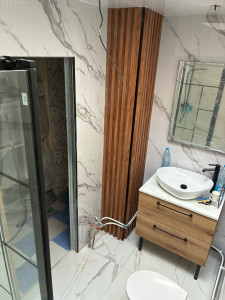 Photo de galerie - Rénovation de salle de bain avec pose de panneaux PVC effet marbre sur murs et plafond, habillage décoratif effet bois et finitions soignées. Un rendu moderne, élégant et résistant à l’humidité.