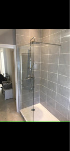 Photo de galerie -  Transformation moderne avec douche à l’italienne 	•	Carrelage mural gris effet pierre, joints blancs 	•	Paroi en verre transparente pour un effet ouvert 	•	Robinetterie chromée avec pommeau de douche effet pluie 	•	Sol plus clair et uniforme