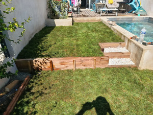 Photo de galerie - Pose gazon en plaques avec arrosage automatique sur 35 M2 avec deux niveaux créés avec poutres bois traité classe 4 et finition graviers blanc décoratif.