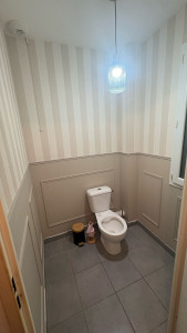 Photo de galerie - Pose de papier de peint sur la première partie du mur, puis création de sous-bassement avec contours en moulures. Finitions peintures sur la deuxièmes partie du mur.
